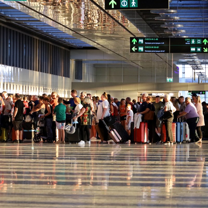 Tourists standing with luggage in queue in the airport