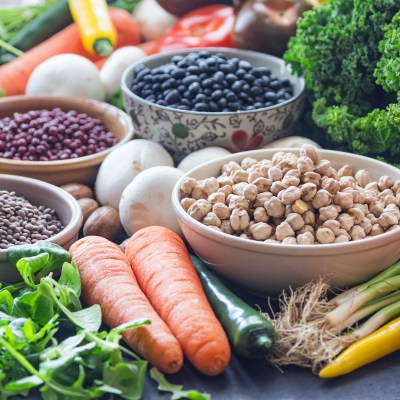 A table with bowls of beans and mixed vegetables.