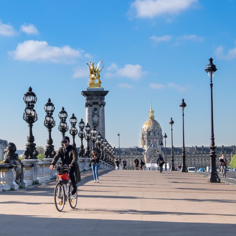 Early morning pedestrians and cyclists on Pont Alexandre III in Paris