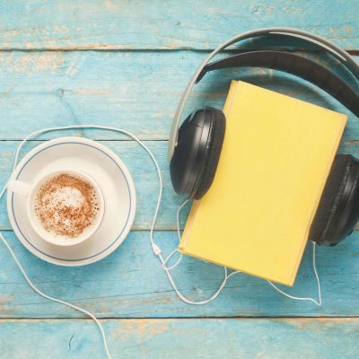 Cup of coffee next to a book and headphones