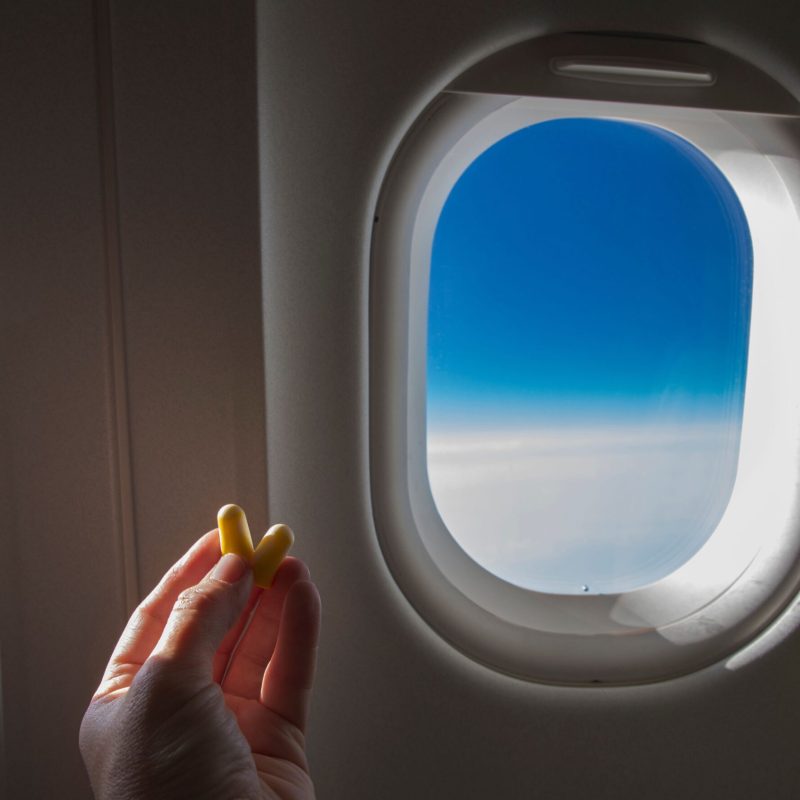 Hand holding earplugs on airplane