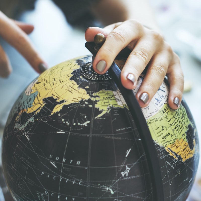 Hands touching and pointing to a globe.