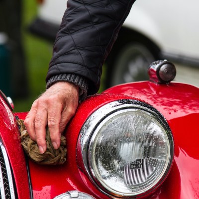 Person washing the front of a classic car.