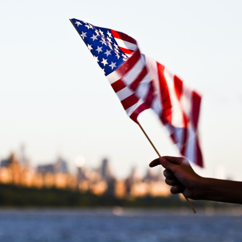 American flag waving with New York City in the background.