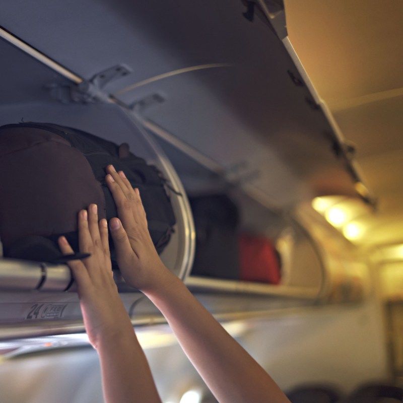 Overhead bin being loaded on a plane.