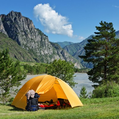 Yellow tent pitched near gorgeous alpine water