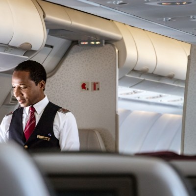 A male cabin crew flight attendant speaking with a passenger onboard on Airbus A350 of Qatar Airways.