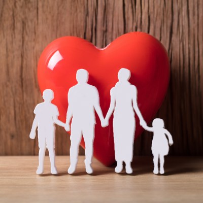 Close-up Of A Family Holding Hands Besides Red Heart Shape