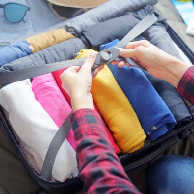 woman packs basic travel clothing into a suitcase