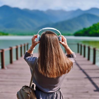 women putting on headphones on a lake dock