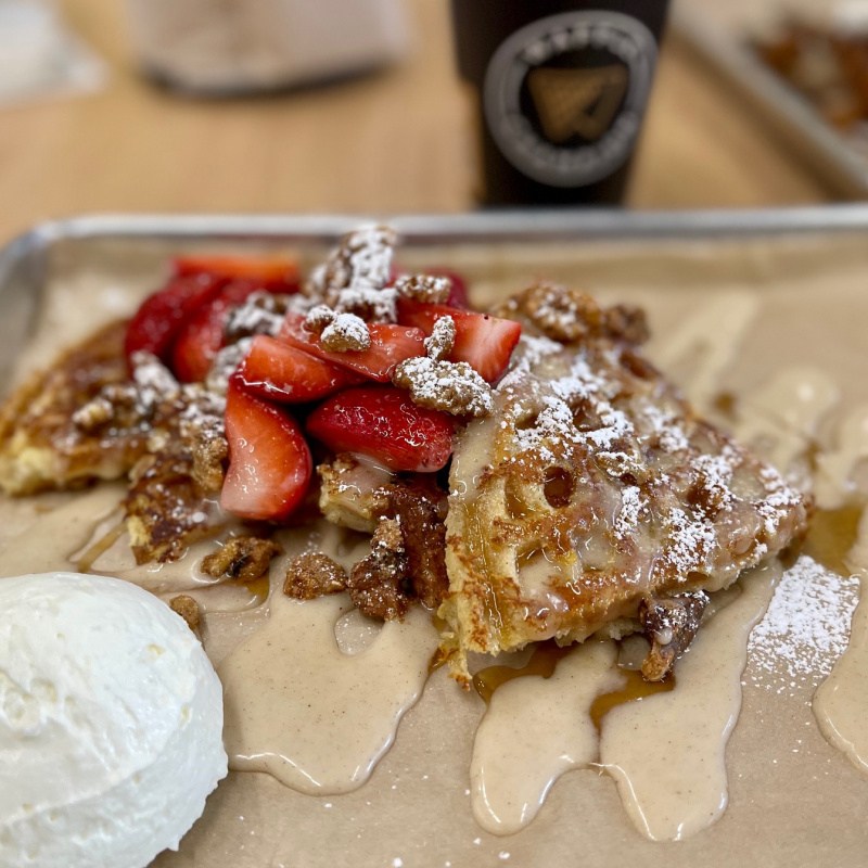 waffles on tray with strawberries and whipped cream