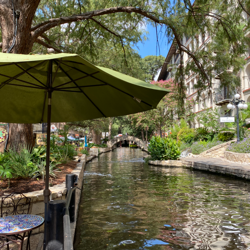 green umbrella at table on riverwalk