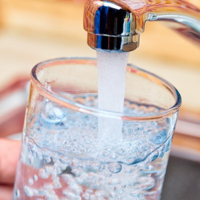 Closeup shot of a man pouring a glass of fresh water from a kitchen faucet