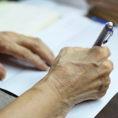 Close-up of woman's hands writing a note.