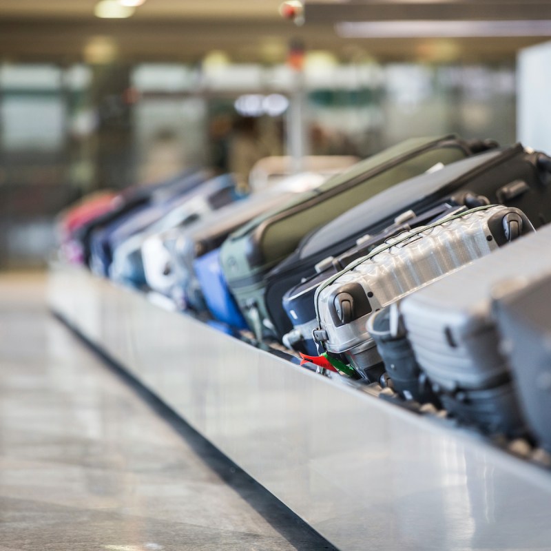 Wheeled suitcase on a luggage belt at the airport terminal.