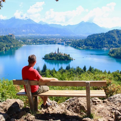 Man resting on a bench on top of the hill, looking at spectacular landscape of Lake Bled