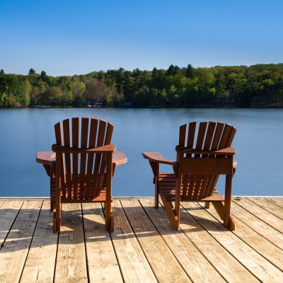 Two chairs sitting next to a calm lake