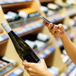 Shopper checks bottle of wine in store