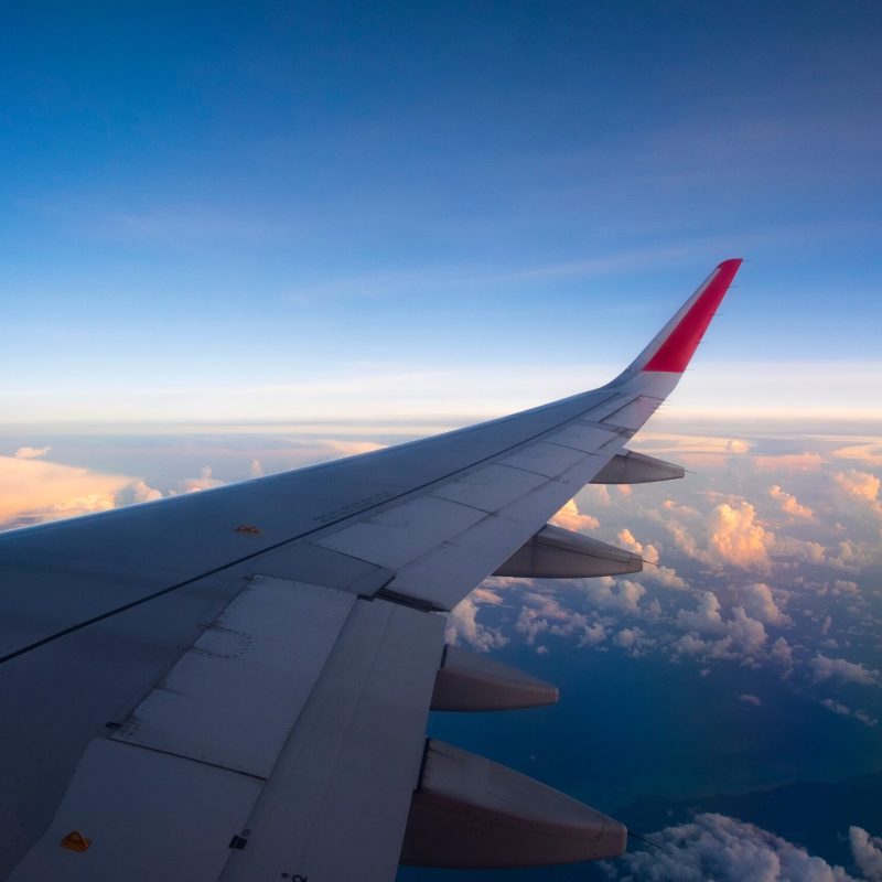 View of airplane wing above clouds from passenger window