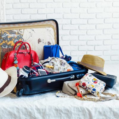 Women's clothes and essential travel items in suitcase