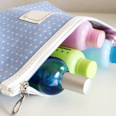 Blue travel toiletry bag with travel toiletries, small plastic bottles of hygiene products and perfume.