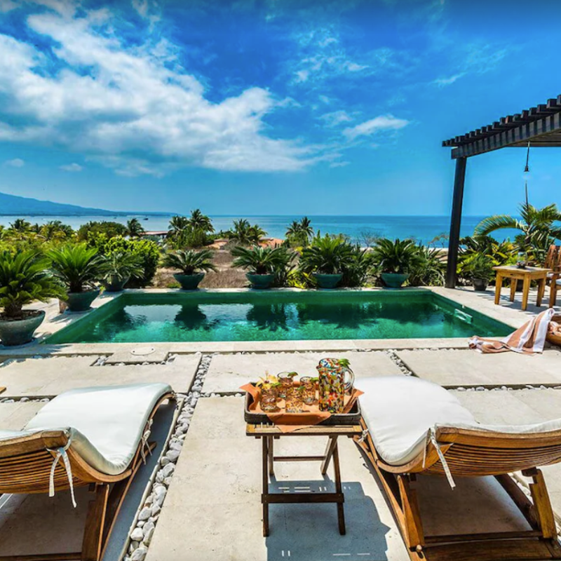 two lounge chairs in front of pool, looking out onto water