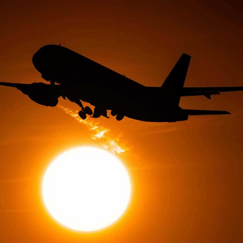 Airplane on takeoff flying across the solar disk, the engine leaves a trail of hot air