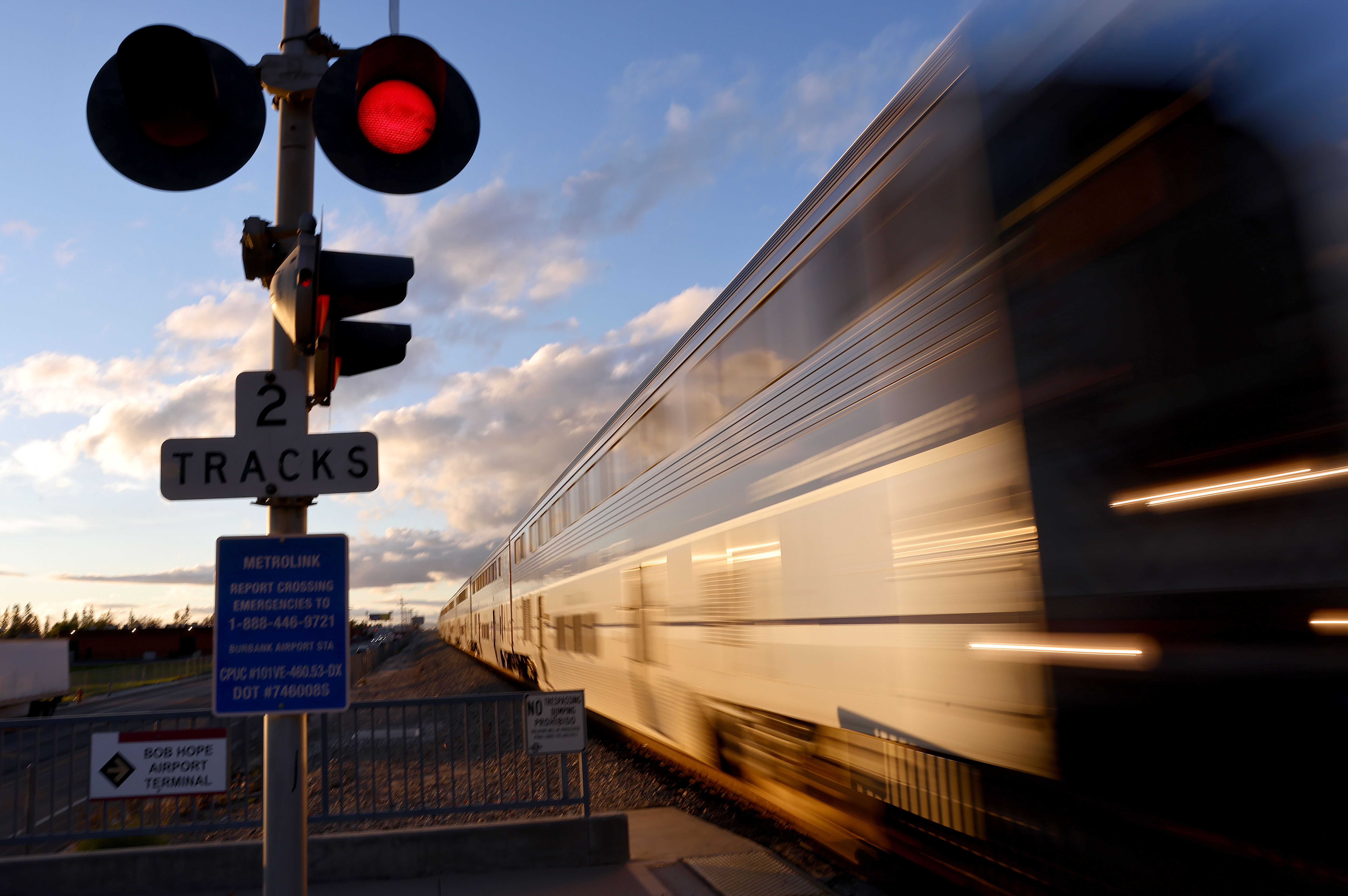 An Amtrak train zooms past an intersection at high speed.
